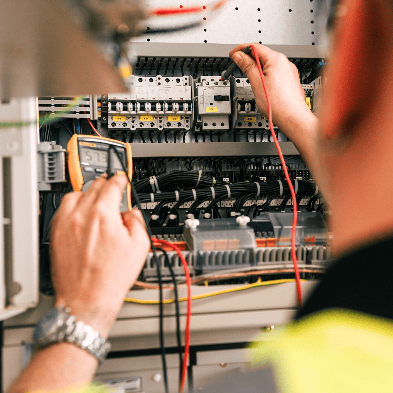 Elektriker überprüft elektrische Schaltanlage mit Messgerät.